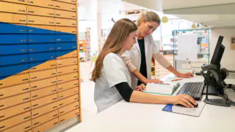 A pharmacist helps a trainee pharmacist