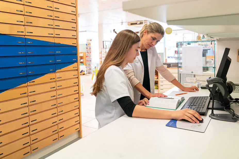 A pharmacist helps a trainee pharmacist