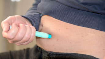 A man injects himself in the abdomen with a weight-loss pen