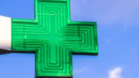 A green cross sign in a community pharmacy