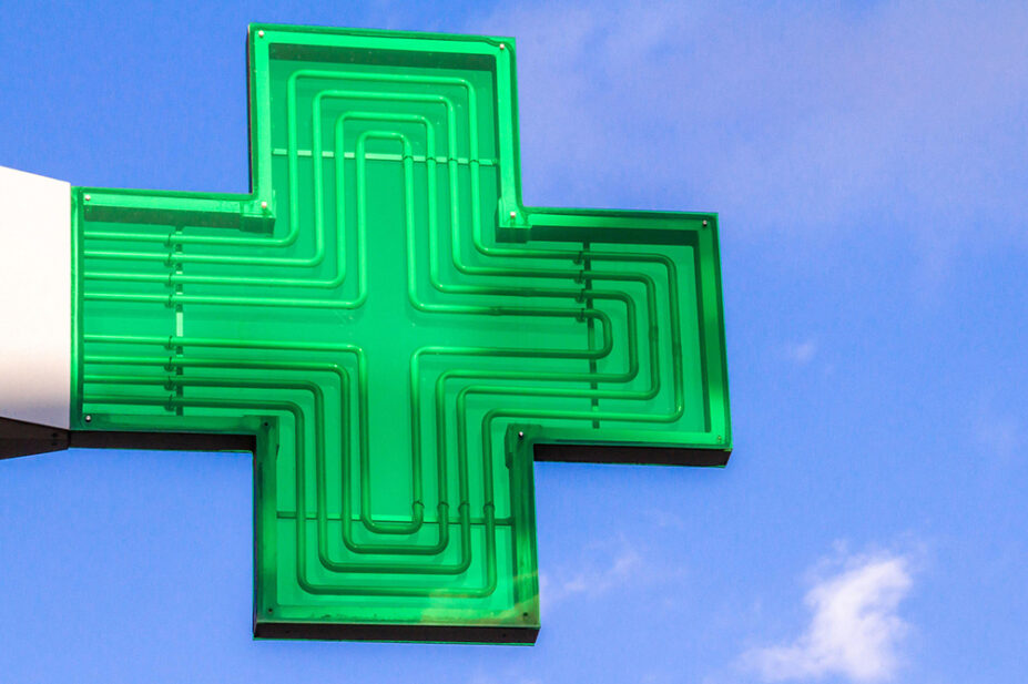 A green cross sign in a community pharmacy