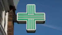A green cross sign in a community pharmacy