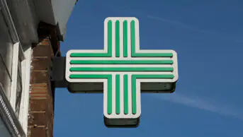 A green cross sign in a community pharmacy