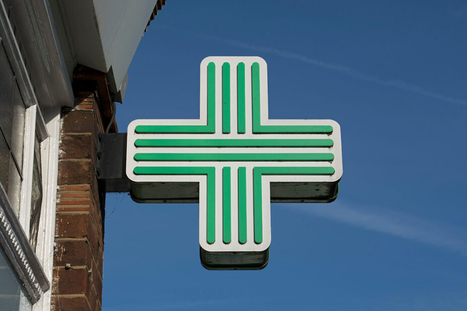 A green cross sign in a community pharmacy