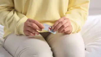 A woman holds a blister pack of emergency contraception
