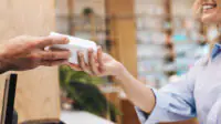 A pharmacist hands a patient a box of medication