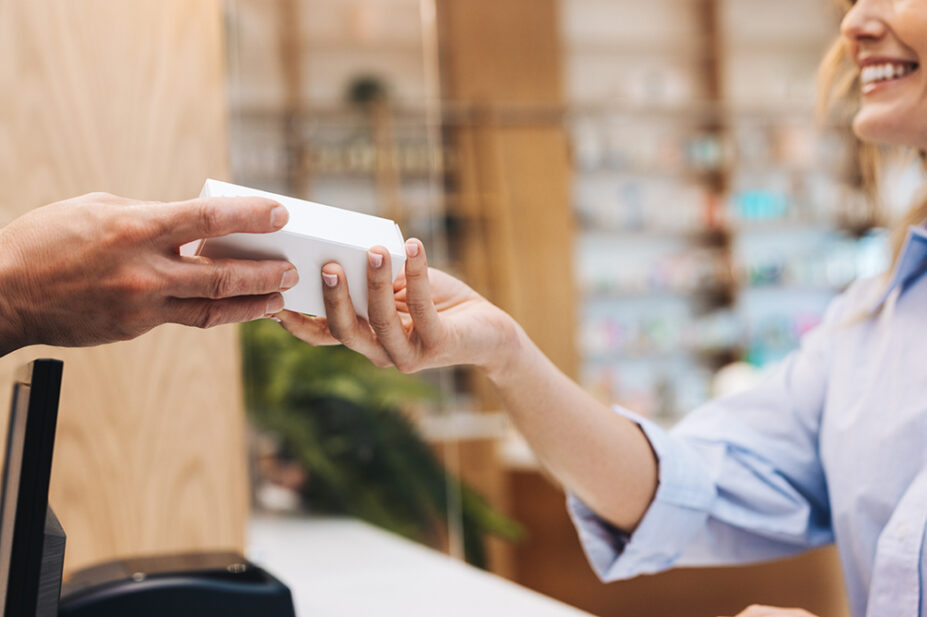 A pharmacist hands a patient a box of medication