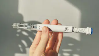 A person holds a GLP-1 weight-loss injection pen