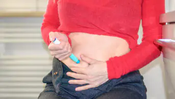A woman injects a weight-loss pen into her abdomen