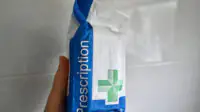 A person holds an NHS branded prescription bag