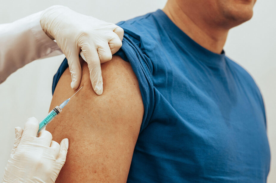 An older man receives a vaccine in his upper arm