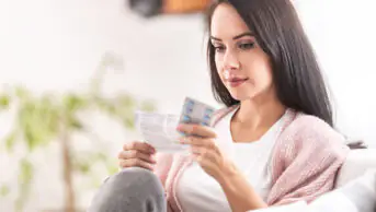 A woman reads a patient information leaflet before taking medication