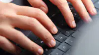 A close-up image of a person typing on a computer keyboard