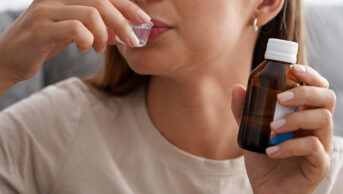 A woman drinks an oral solution of a medication