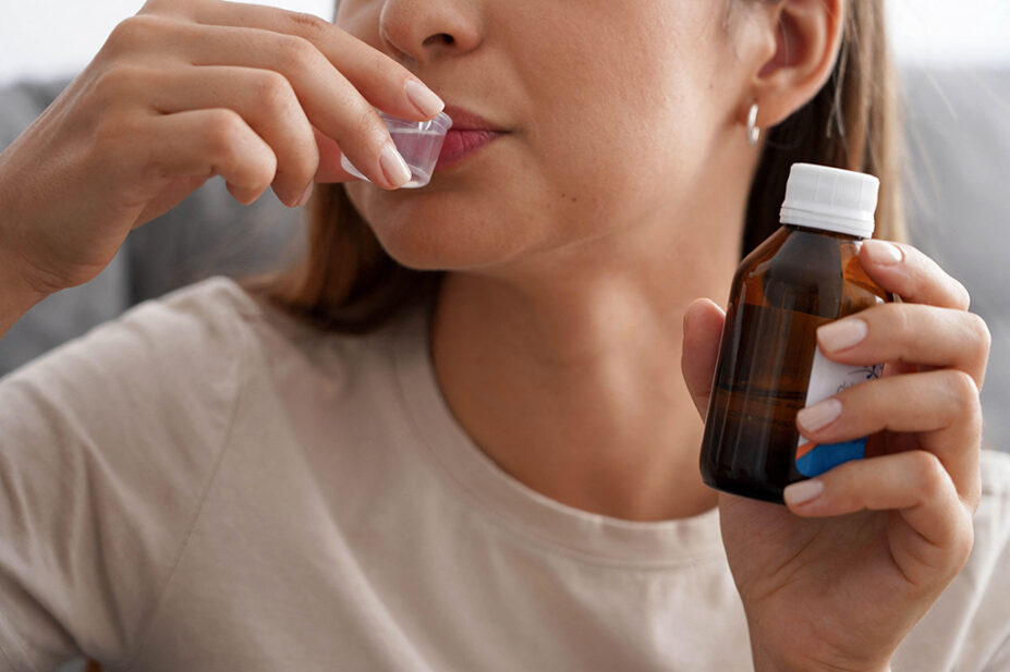 A woman drinks an oral solution of a medication