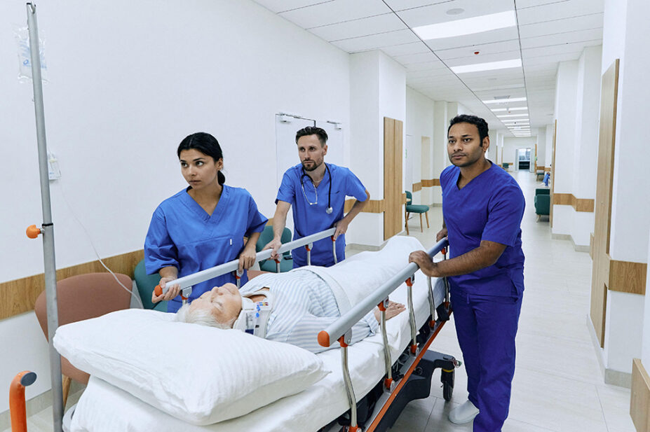 Nurses wheel a patient through a hospital corridor
