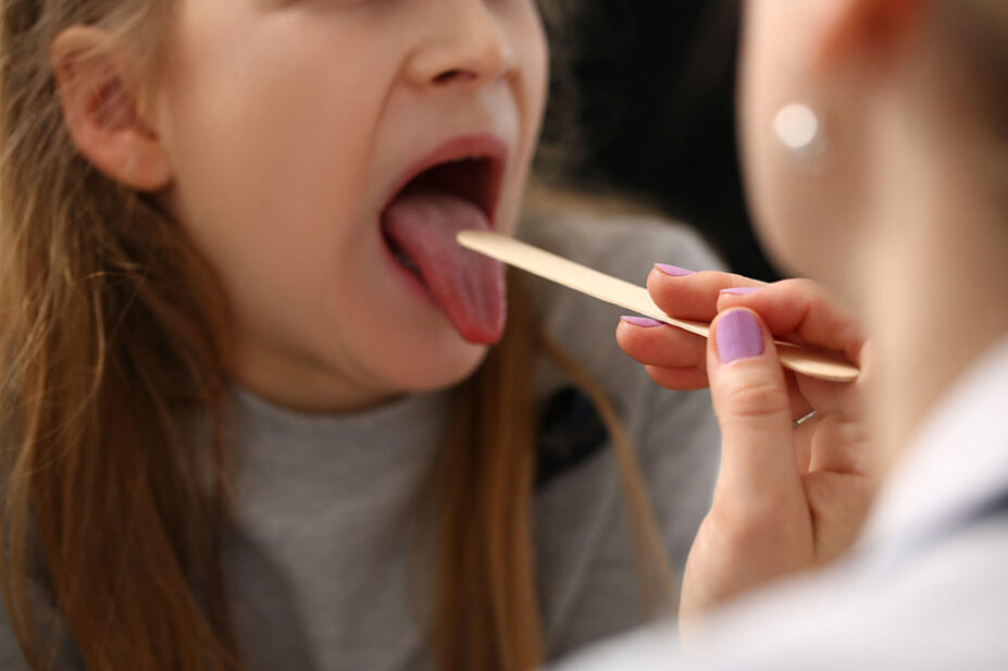 A healthcare professional checks the sore throat of a patient