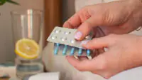 Female hands holding various blisters with medicines in the bedroom