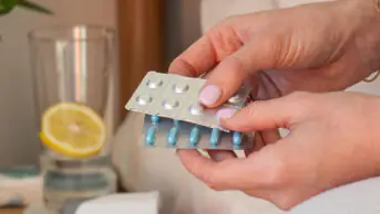 Female hands holding various blisters with medicines in the bedroom