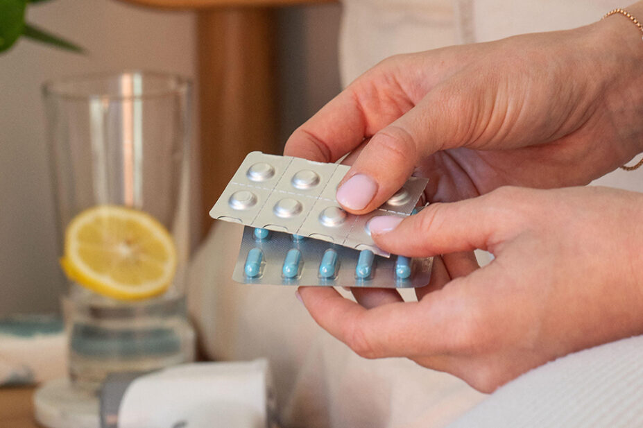 Female hands holding various blisters with medicines in the bedroom