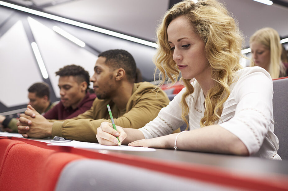 Female student taking notes in a university lecture theatre