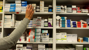 A pharmacist stocking shelves in a pharmacy